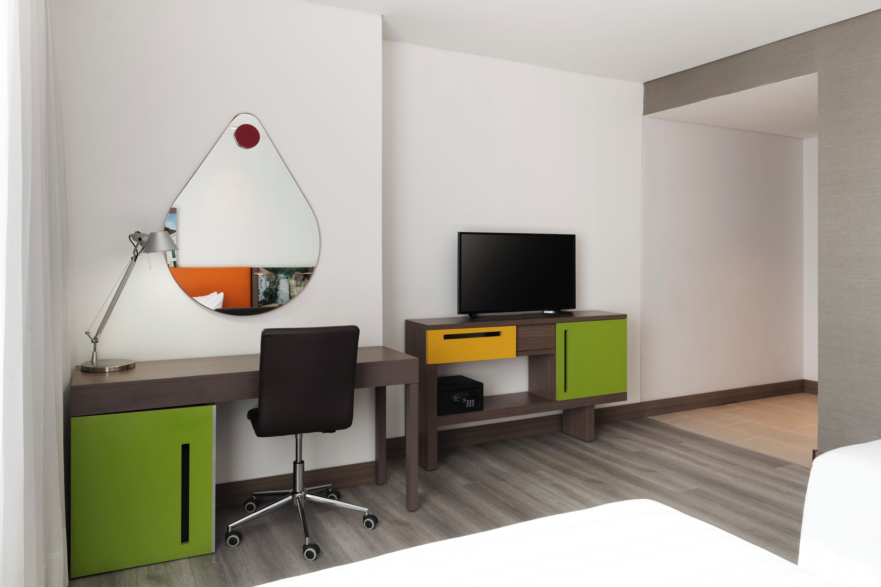 Habitación de hotel con escritorio, silla, televisor y cama.