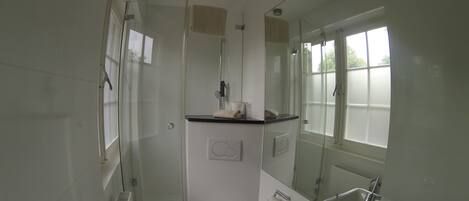 A compact bathroom with a shower, toilet, and sink.