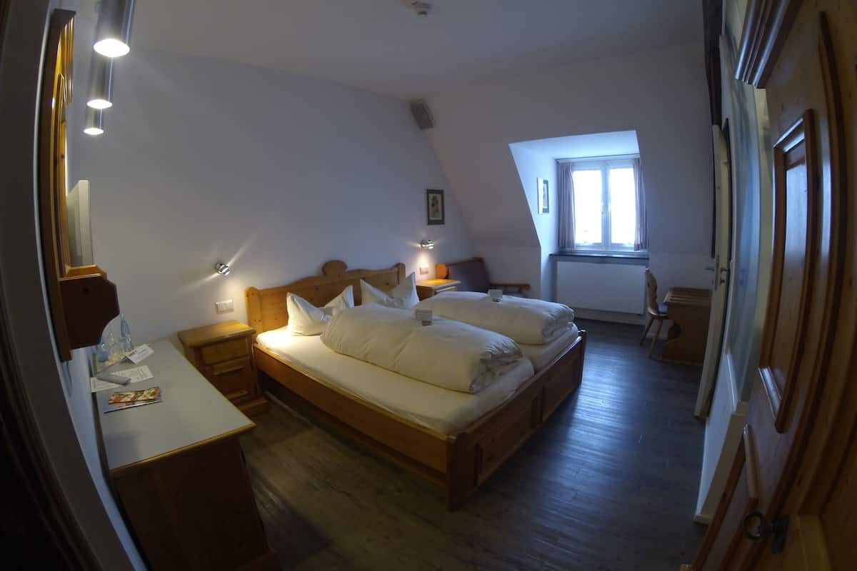 Une chambre à coucher avec un lit en bois, des tables de chevet, un bureau et une fenêtre avec des rideaux.
