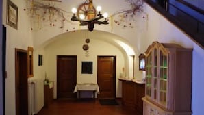 A hallway with an arched ceiling, wooden doors, a table with a white tablecloth, and a wooden cabinet with glass doors.