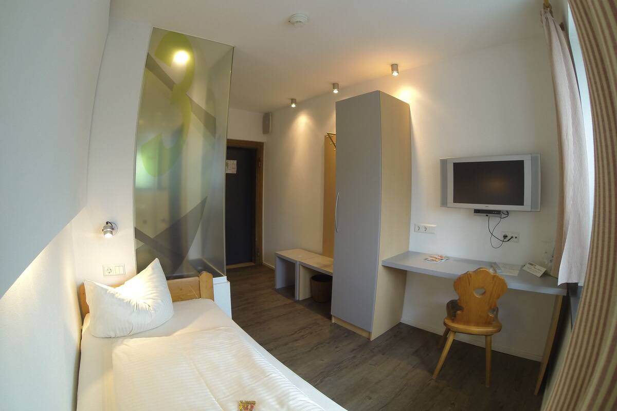 Une chambre d’hôtel avec un lit, un bureau, une chaise, une télévision et un miroir.