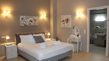A modern bedroom with a large bed, bedside lamps, a nightstand, a dresser, and a mirror.
