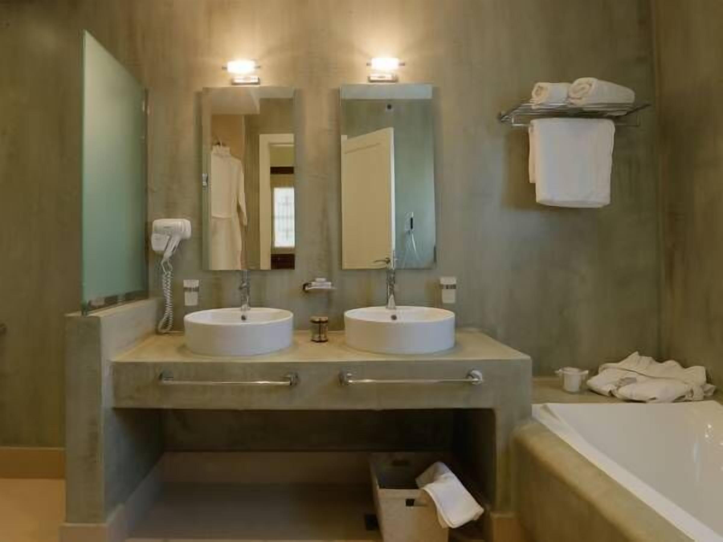 A bathroom with two sinks, a mirror, a towel rack, and a bathtub.