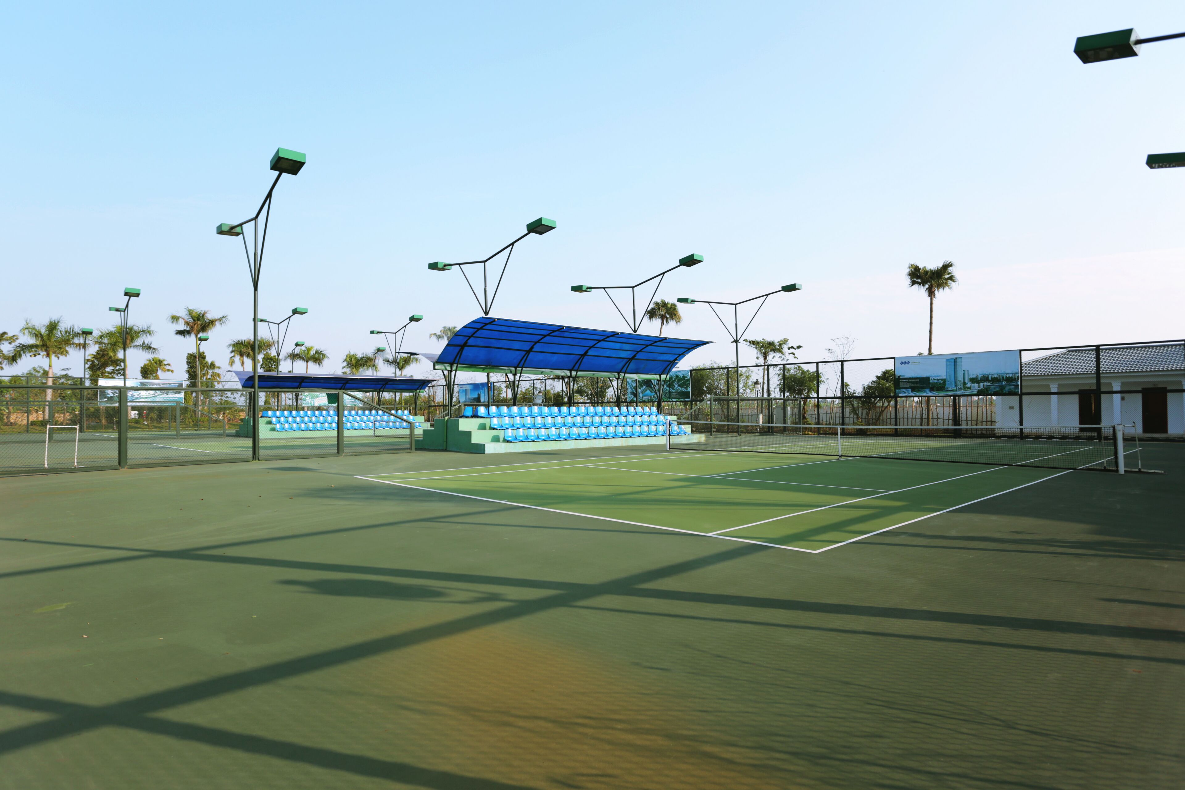 A tennis court with seating areas and solar panels.