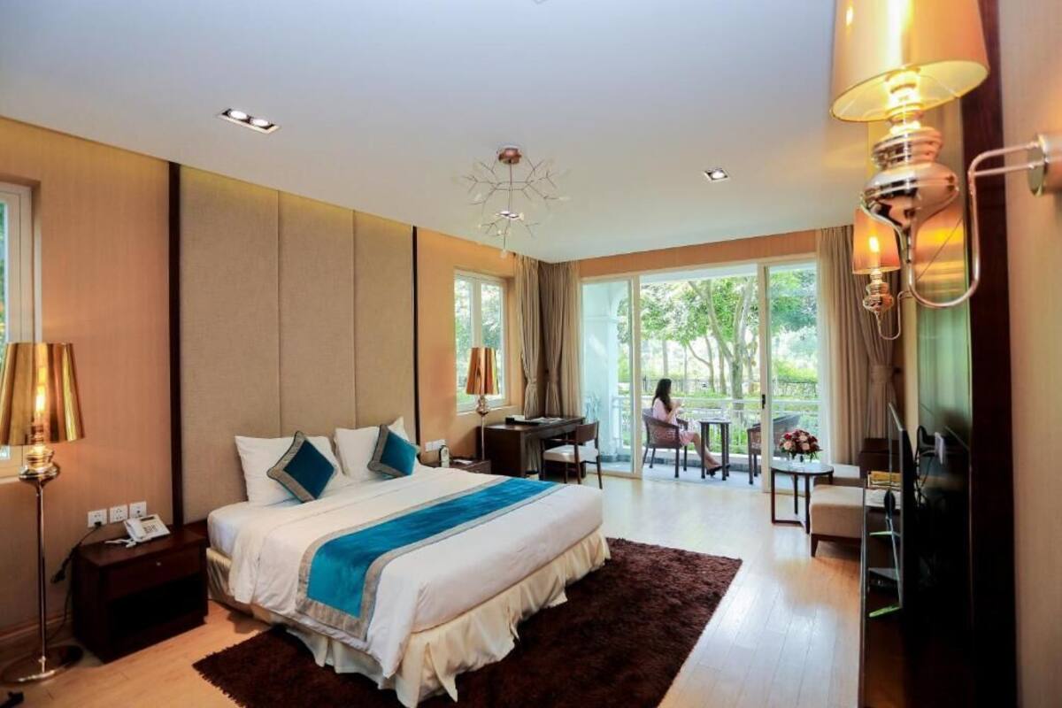 A bedroom with a large bed, a desk, and a view of the outdoors.