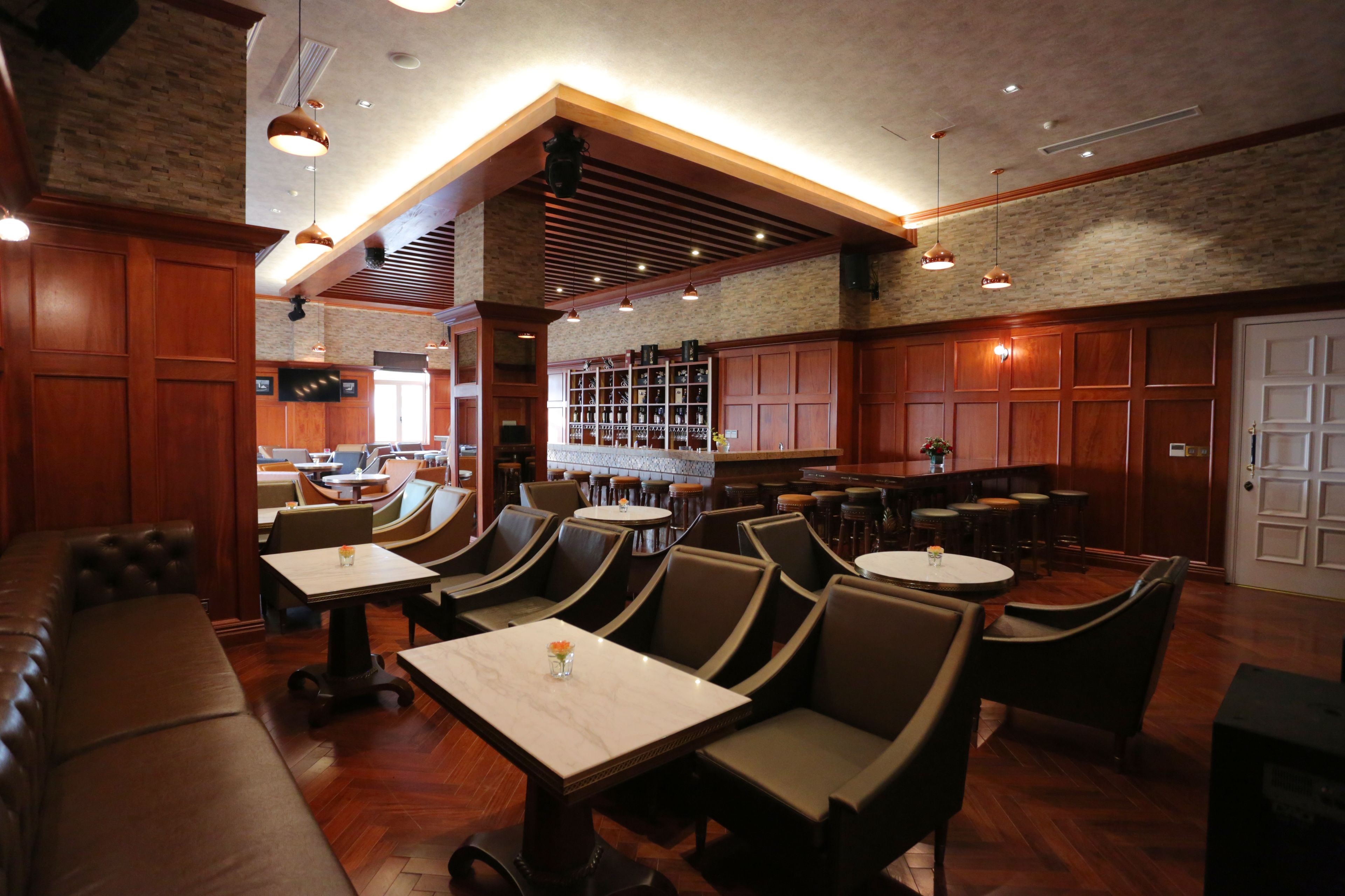 A restaurant with wooden booths, round tables, and a bar area.
