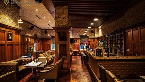 A restaurant with wooden booths, a bar area, and a herringbone wood floor. - FLC Luxury Resort Vinh Phuc (Vinh Phu)