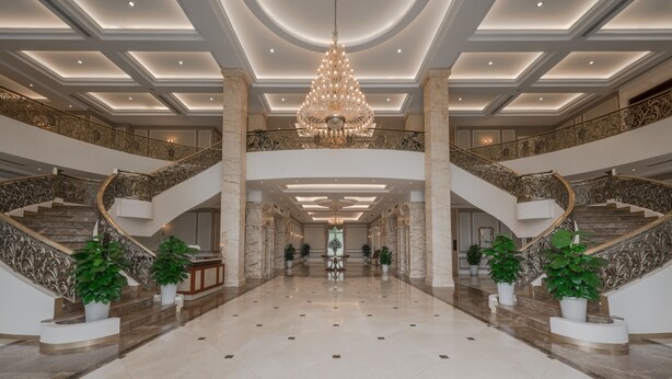 A grand lobby with a central chandelier, marble flooring, and ornate staircases. - FLC Luxury Resort Vinh Phuc (Vinh Phu)