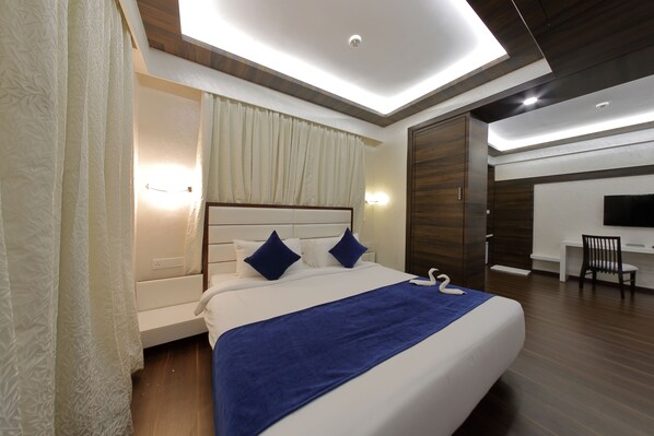 A modern hotel room with a large bed, a desk, and a TV.