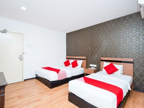 A hotel room with two beds, each with white bedding and red pillows, a wooden floor, and a patterned wallpaper on the wall. - OYO 504 Hotel Aromas Kulai (Kulai)