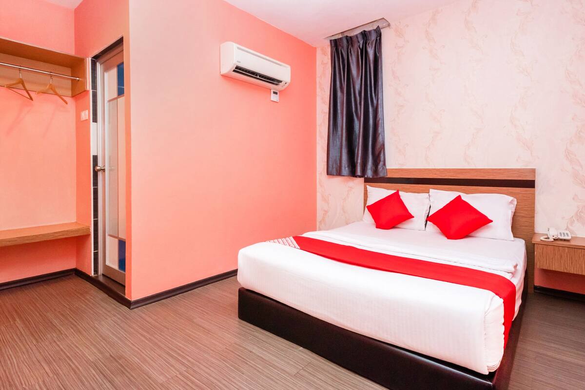 A hotel room with a bed, a wardrobe, and an air conditioning unit.