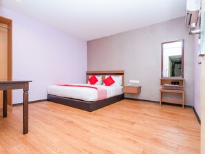 A hotel room with a bed, bedside table, and a mirror.