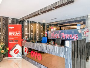 A hotel reception desk with a sign reading "Hotel Aromas" and a red OYO app advertisement. - OYO 504 Hotel Aromas Kulai (Kulai)