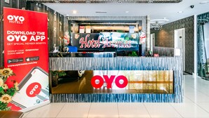 Zona de recepción de un hotel con diseño moderno, que destaca con un logotipo prominente de 'OYO' y un cartel que dice 'Hotel Aromas'.