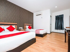 A hotel room with two beds, a wooden floor, a wall air conditioner, and a dark curtain.