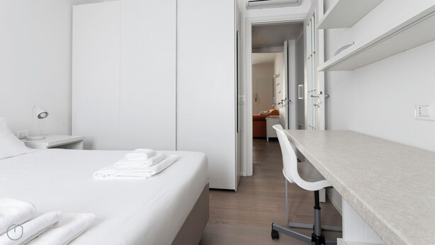 A modern hotel room with a neatly made bed, a desk with a chair, and a bathroom visible through an open door. - Italianway Comfort - Bligny 19 A (Milan)