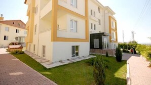 A multi-story residential building with a modern design, featuring a flat roof, large windows, and a well-maintained lawn. - Fimaj Residence & Apart Hotel (Kayseri)