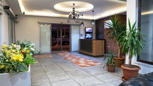 A hotel lobby with a reception desk, a chandelier, potted plants, and a tiled floor. - Fimaj Residence & Apart Hotel (Kayseri)