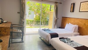 Une chambre d’hôtel avec un lit, un bureau et une vue sur la verdure, accessible par une porte coulissante.