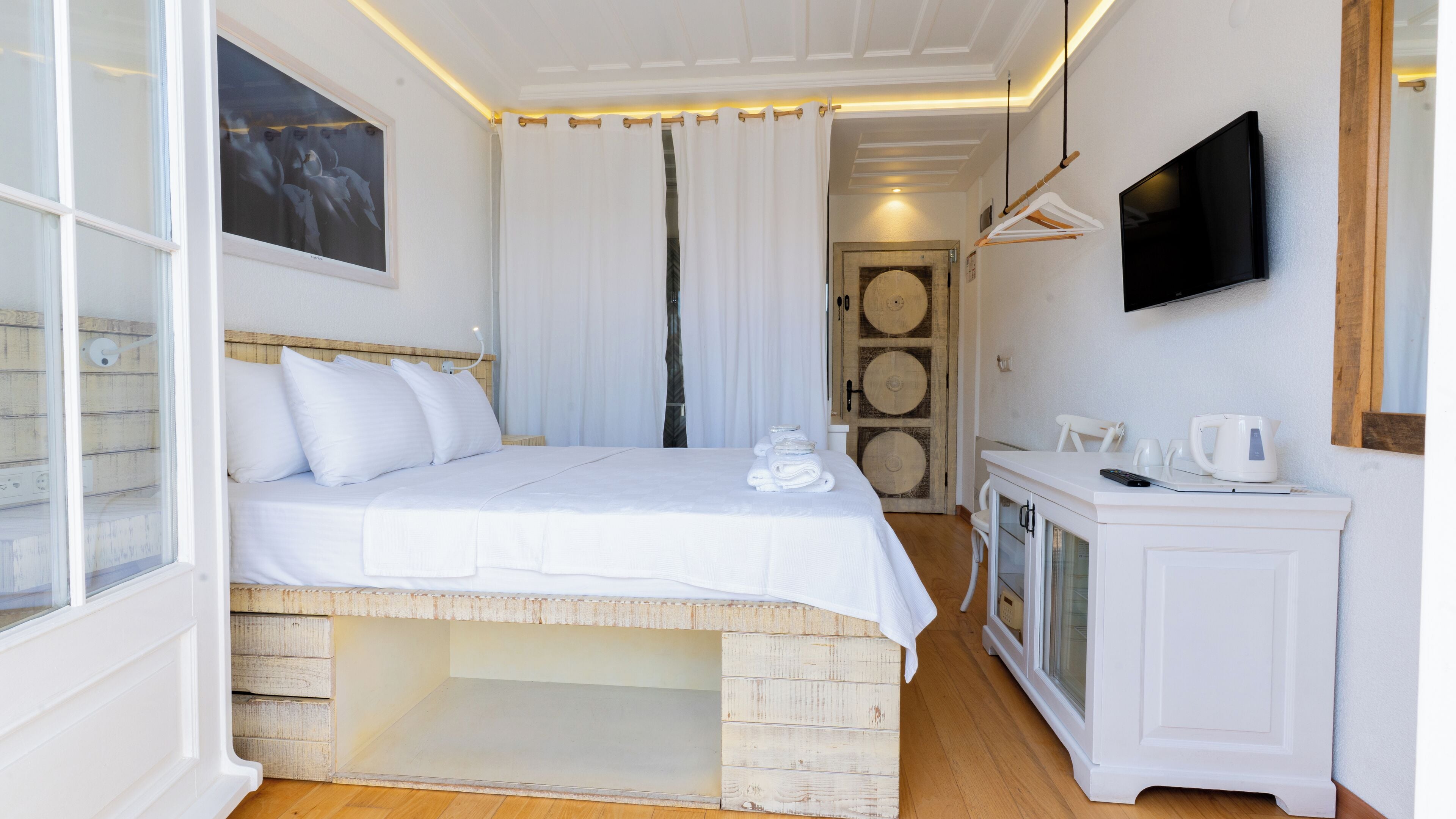 Un dormitorio con cama, una mesita de noche con tetera, televisor y un armario de madera.