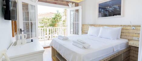 Habitación de hotel con cama, escritorio, televisor y balcón con vistas al exterior.