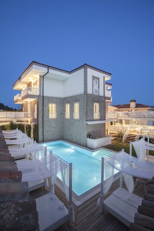 Una piscina al aire libre, sombrillas, sillones reclinables de piscina