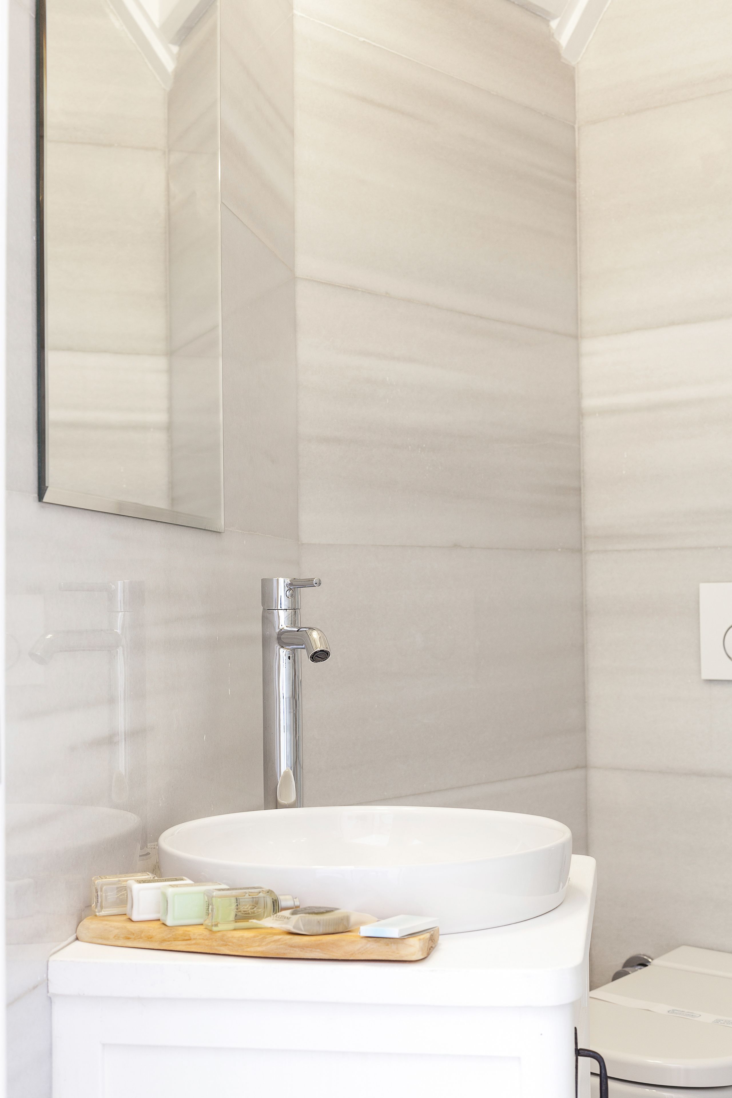 A modern bathroom with a white sink, a mirror, and a toilet.