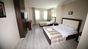 Habitación de hotel con dos camas, televisión, escritorio y ventana con cortinas.