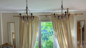 A bedroom with a large window, a bed, a chair, and a chandelier. - Verdmont (Acqui Terme)