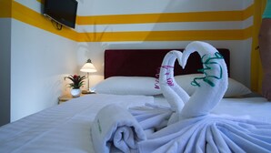 A hotel room with a bed, a TV mounted on the wall, a nightstand with a lamp and a plant, and a decorative towel arrangement on the bed. - Hotel City Residence (Vienna)