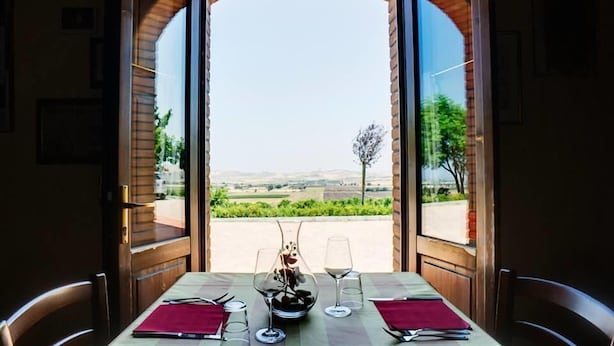 A table set for two with a view of a vineyard through an open archway. - Relais I Dolci Grappoli (Larino)