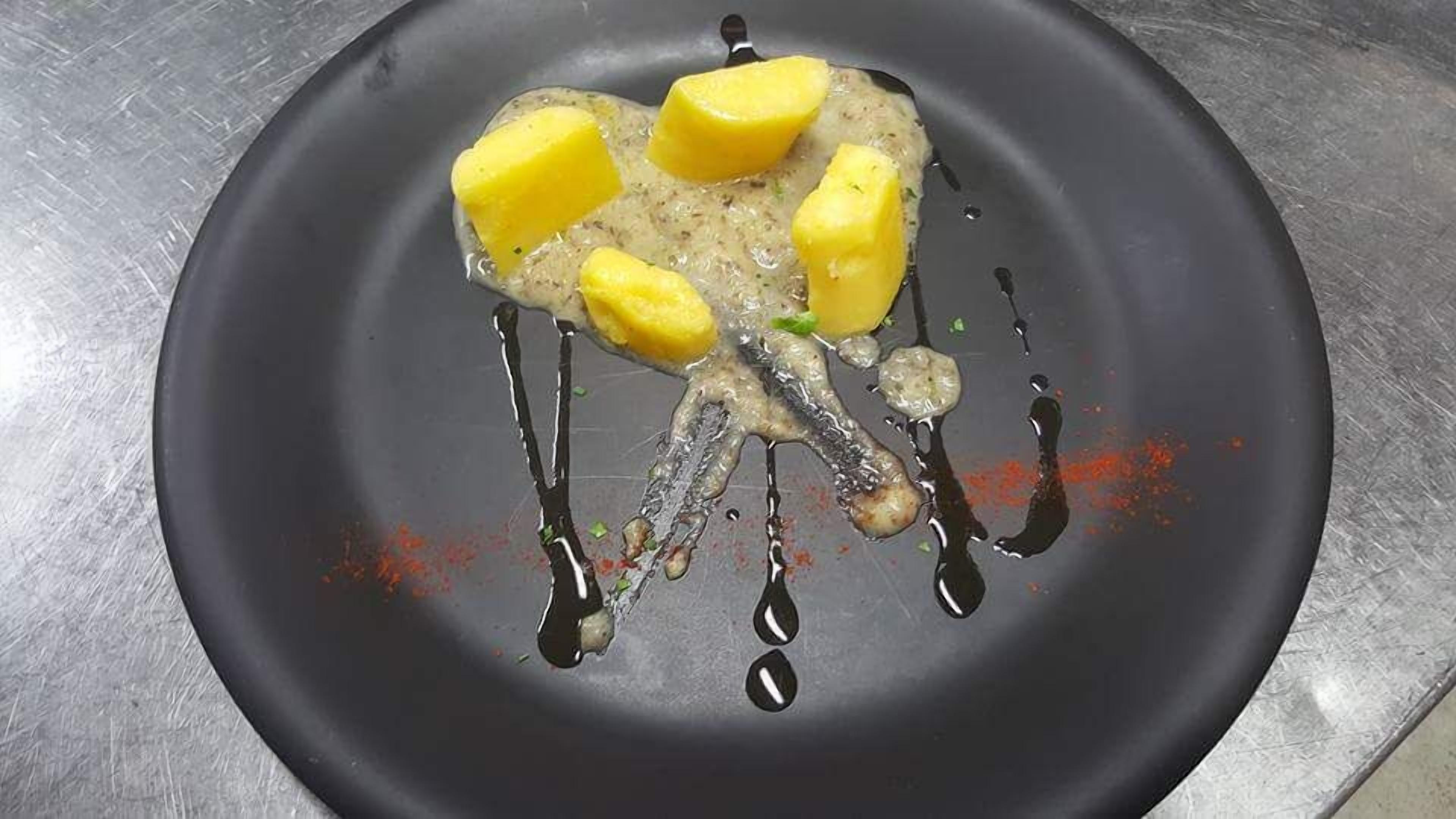 Un plato con un trozo de carne, cuartos de limón y salsa.