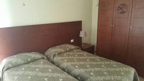 A room with two beds, a nightstand with a lamp, and a wooden wardrobe. - Relais I Dolci Grappoli (Larino)