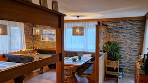 A cozy restaurant with wooden furniture, stone walls, and hanging lights. - Waldpension Schiefling am See (Schiefling am See)