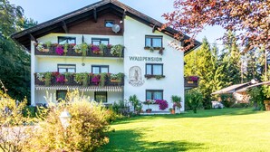 A multi-story building with the name "WALDPENSION" on the facade, balconies with flower boxes, and a well-maintained garden. - Waldpension Schiefling am See (Schiefling am See)