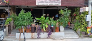 A storefront with a sign for 'Lovely Guest House 94' and a variety of potted plants in front. - Lovely Guesthouse 94 (Hua Hin)