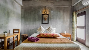 Een slaapkamer met een groot bed, een houten nachtkastje, een bijzettafeltje en een stoel.