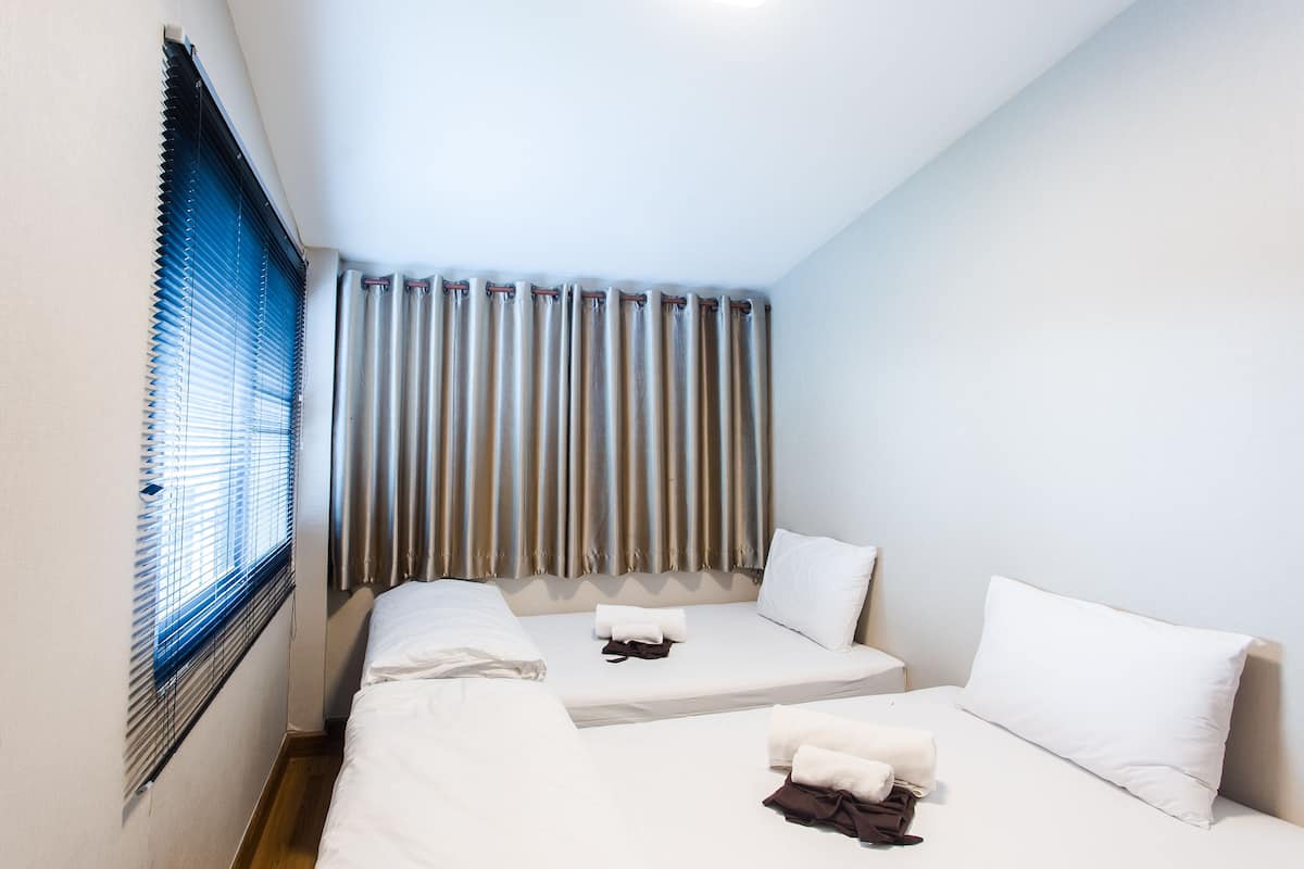 A hotel room with two beds, a window with blinds, and a curtain.