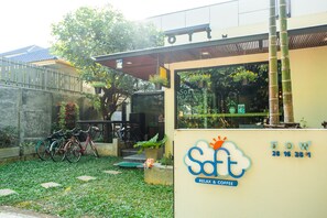 A cafe named 'Soft' with a sign indicating 'Relax & Coffee'. There are bicycles parked outside and a small garden area with steps leading to the entrance.