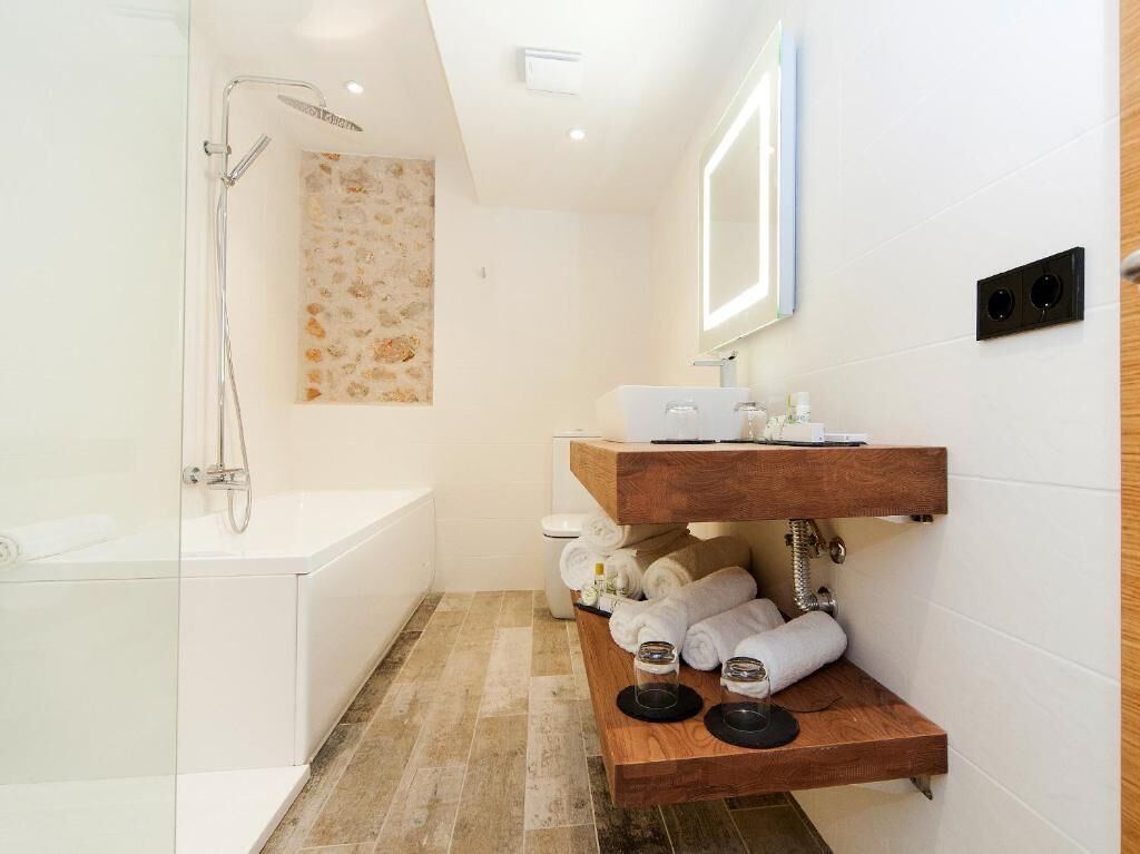 Ein modernes Badezimmer mit einer gläsernen Duschkabine, einem Holzbadezimmer-Möbelstück und ordentlich aufgerollten Handtüchern.
