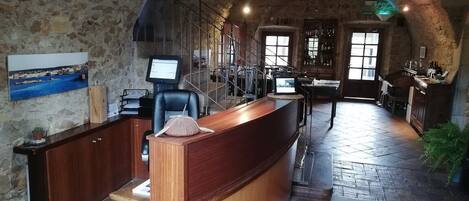 Een rustiek interieur met een receptiebalie, stenen muren, een houten toonbank en een bar.