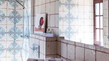 Une salle de bain avec des carreaux décorés, une douche, une serviette portant la marque « Moli de l’Escala » et un tableau encadré accroché au mur.