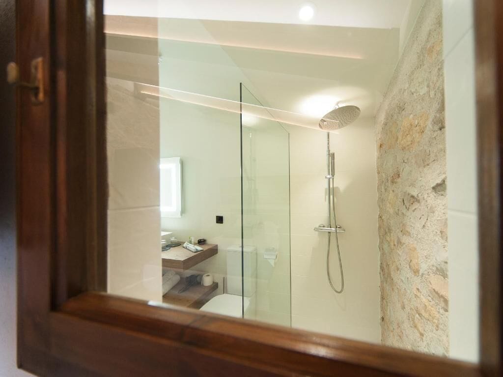 A modern bathroom with a glass shower enclosure, a visible toilet, and a wooden vanity.