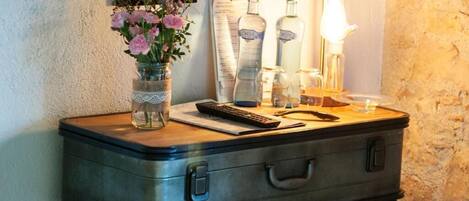 Een bureau in vintage stijl met een koffer, een bloevas, een lamp en enkele flessen.