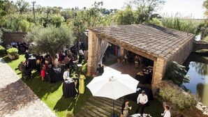 An outdoor event with a stone pavilion, tables, and guests. - Hotel Molí de l'Escala (L'Escala)