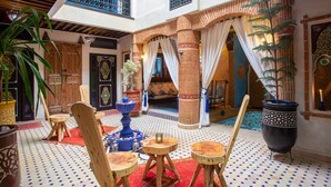 Un interno tradizionale marocchino con un cortile, arredi in legno e elementi decorativi.