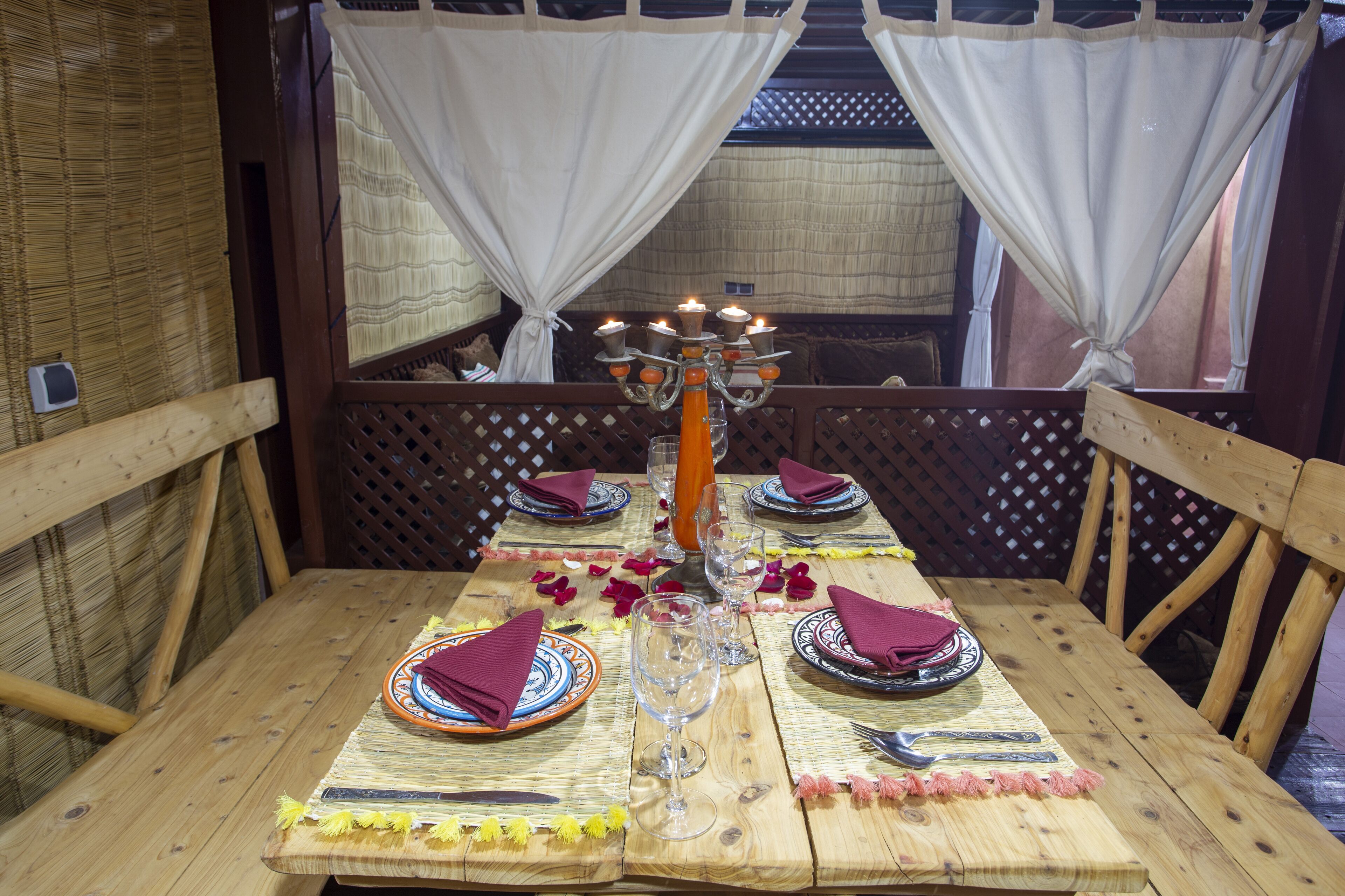 Una mesa de madera dispuesta con platos, vasos y un candelabro.