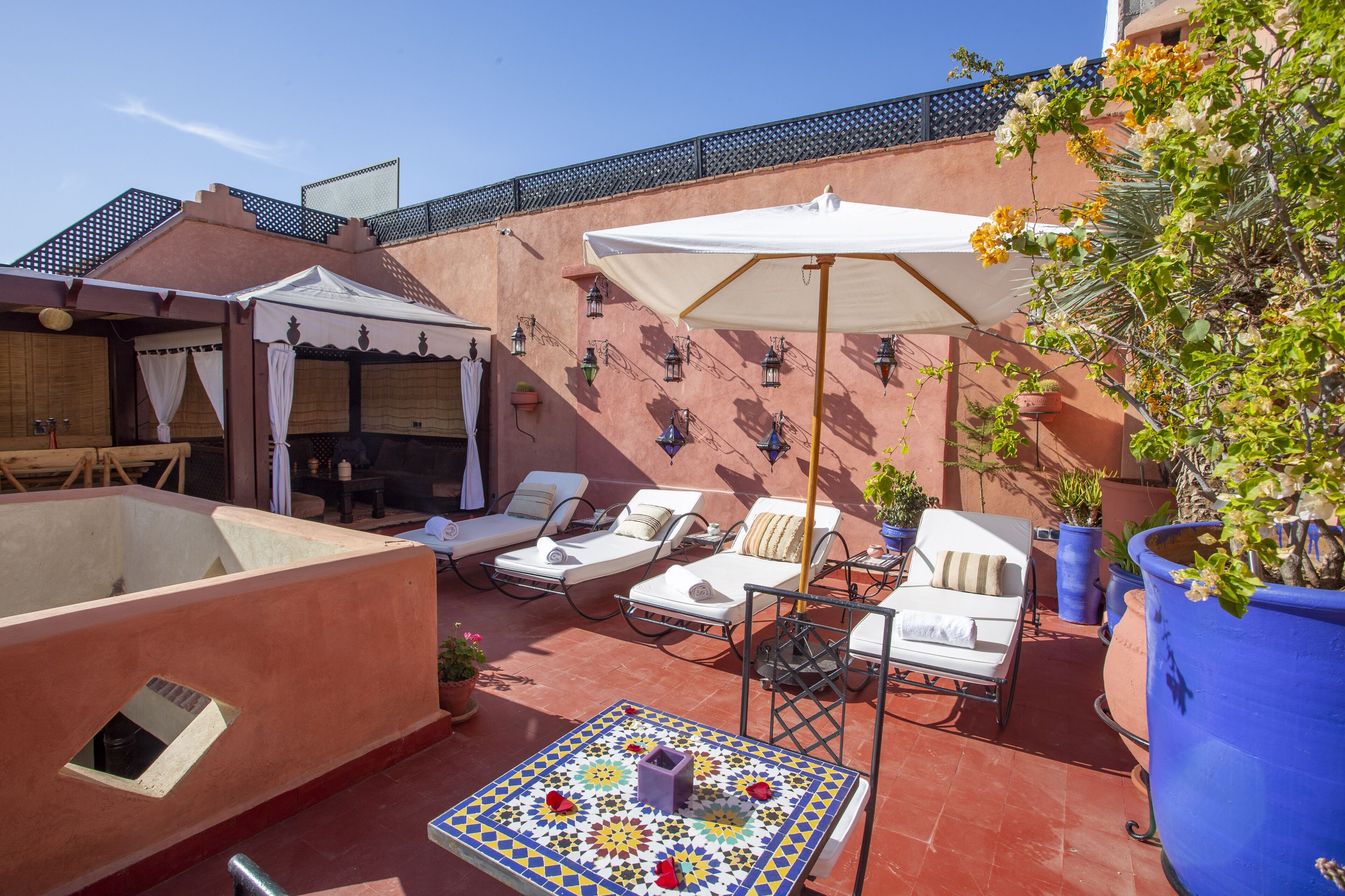 Un patio con sillones de descanso, una mesa y un paraguas blanco.