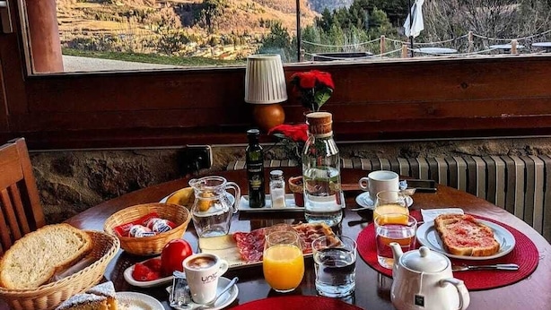 A breakfast table with various food items and a view of a mountainous landscape. - Can Gasparó Hotel Rural & Restaurant (Planoles)