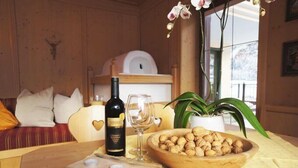 A cozy room with a wooden table, a bottle of wine, a glass, and a bowl of nuts. - Aparthotel Landhaus St. Joseph (Mayrhofen)